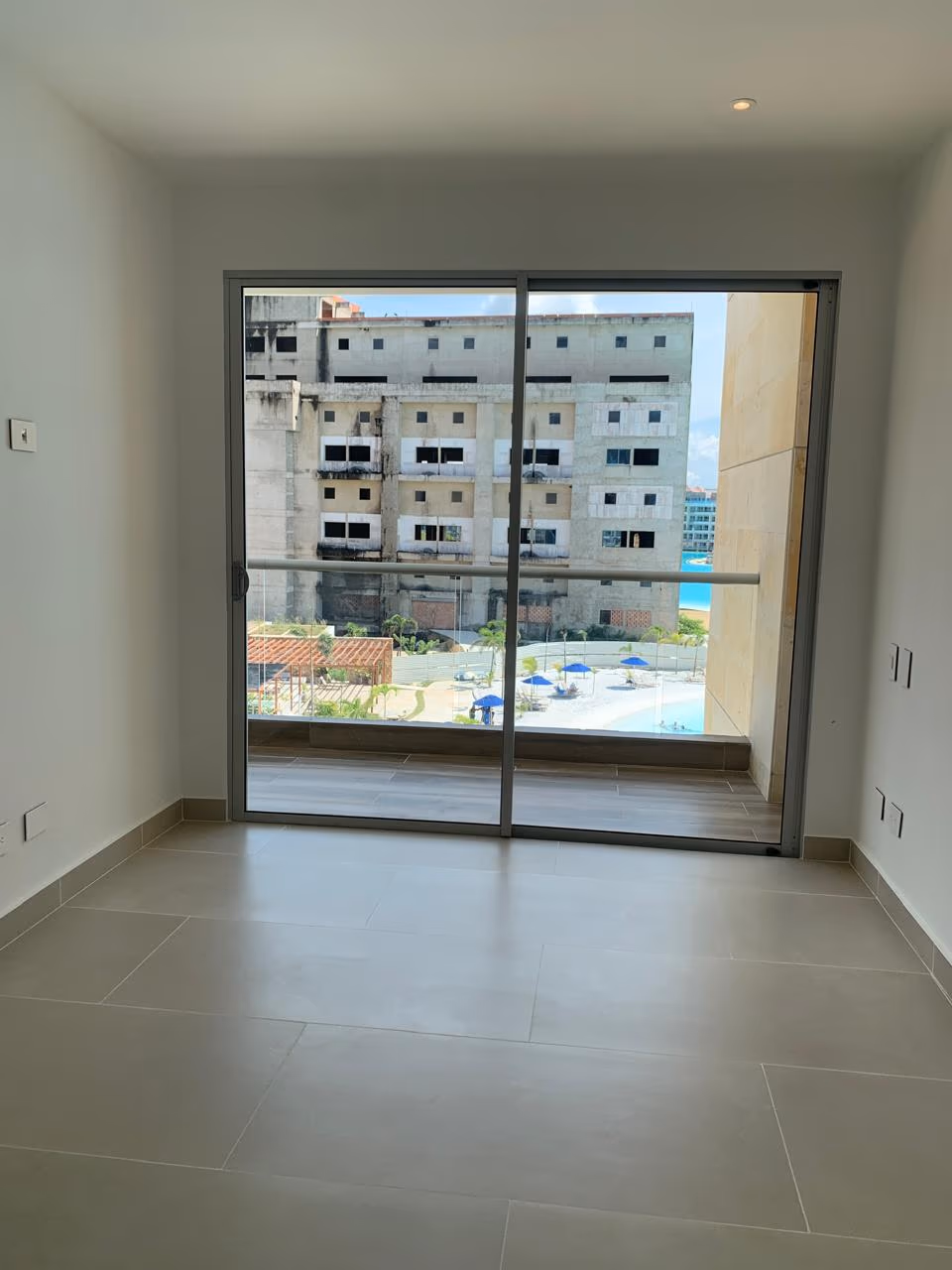 Sala vacía con piso gris y ventanal, sin un solo mueble