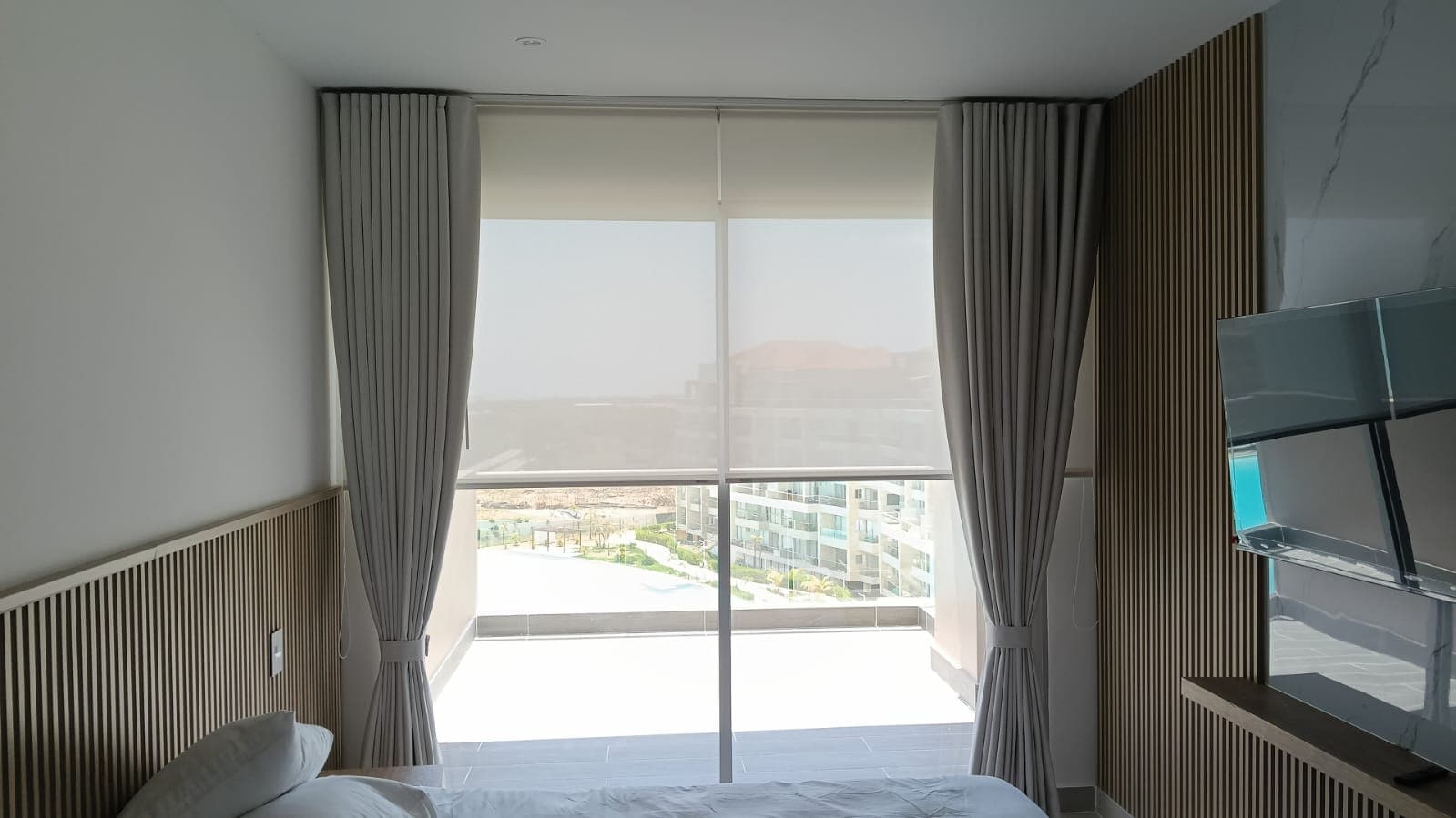 Persiana enrollable solar screen desenrollada filtrando vista panorámica en habitación dotada por Reddy