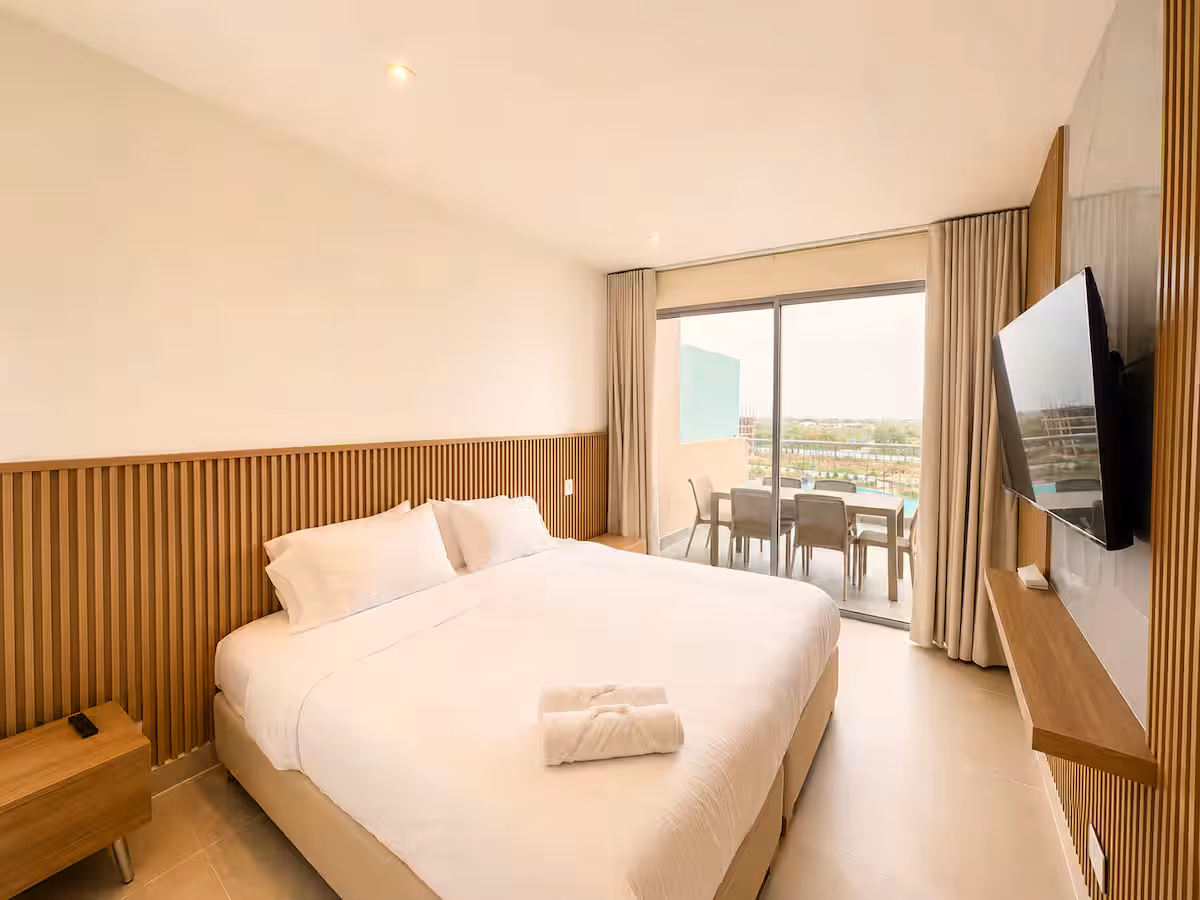 Dormitorio king con panel de listones bajo, TV en mármol y terraza comedor