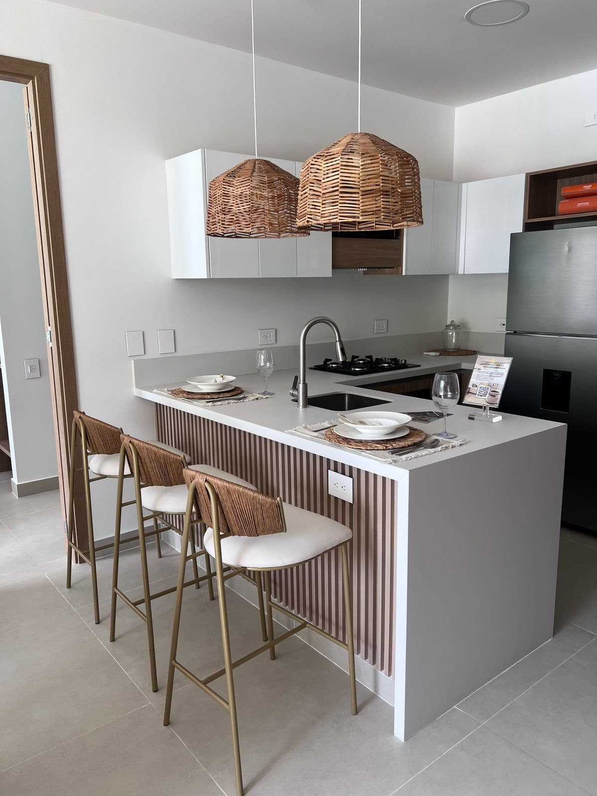 Barra de cocina con frente en panel de listones de madera y sillas mimbre