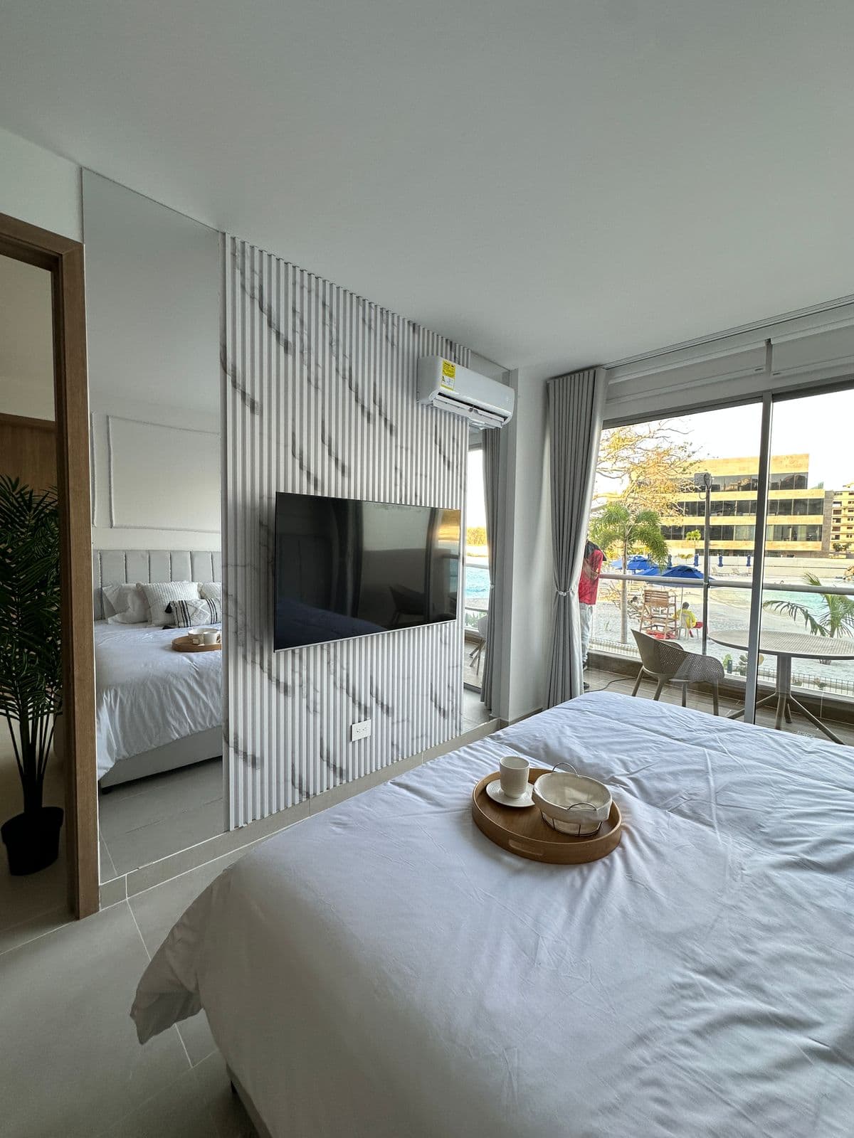 Habitación con panel listones y mármol detrás del TV y vista a piscina