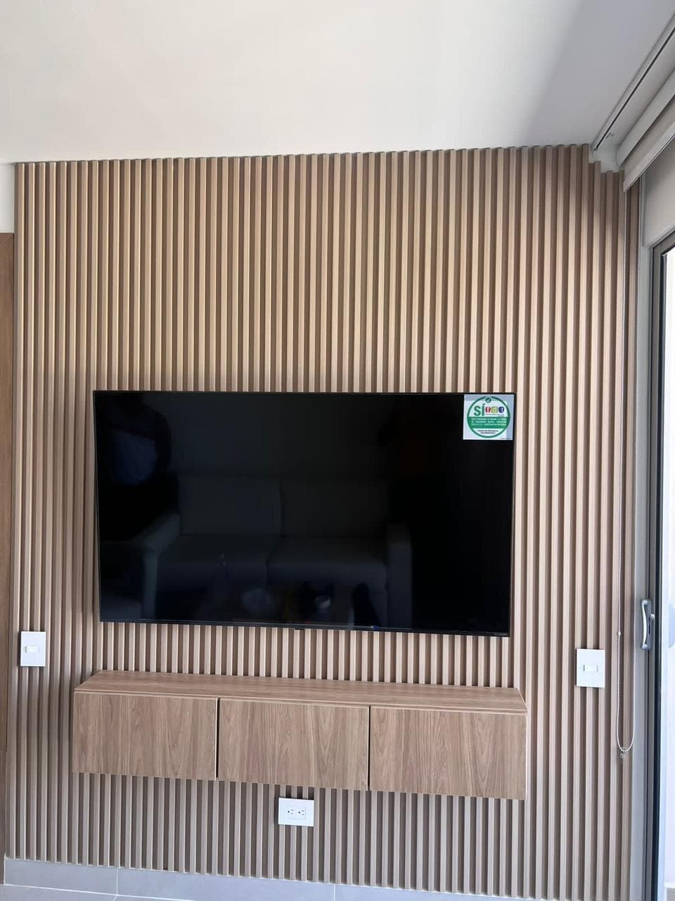 Muro de TV en panel full-wall de listones de madera con mueble bajo flotante