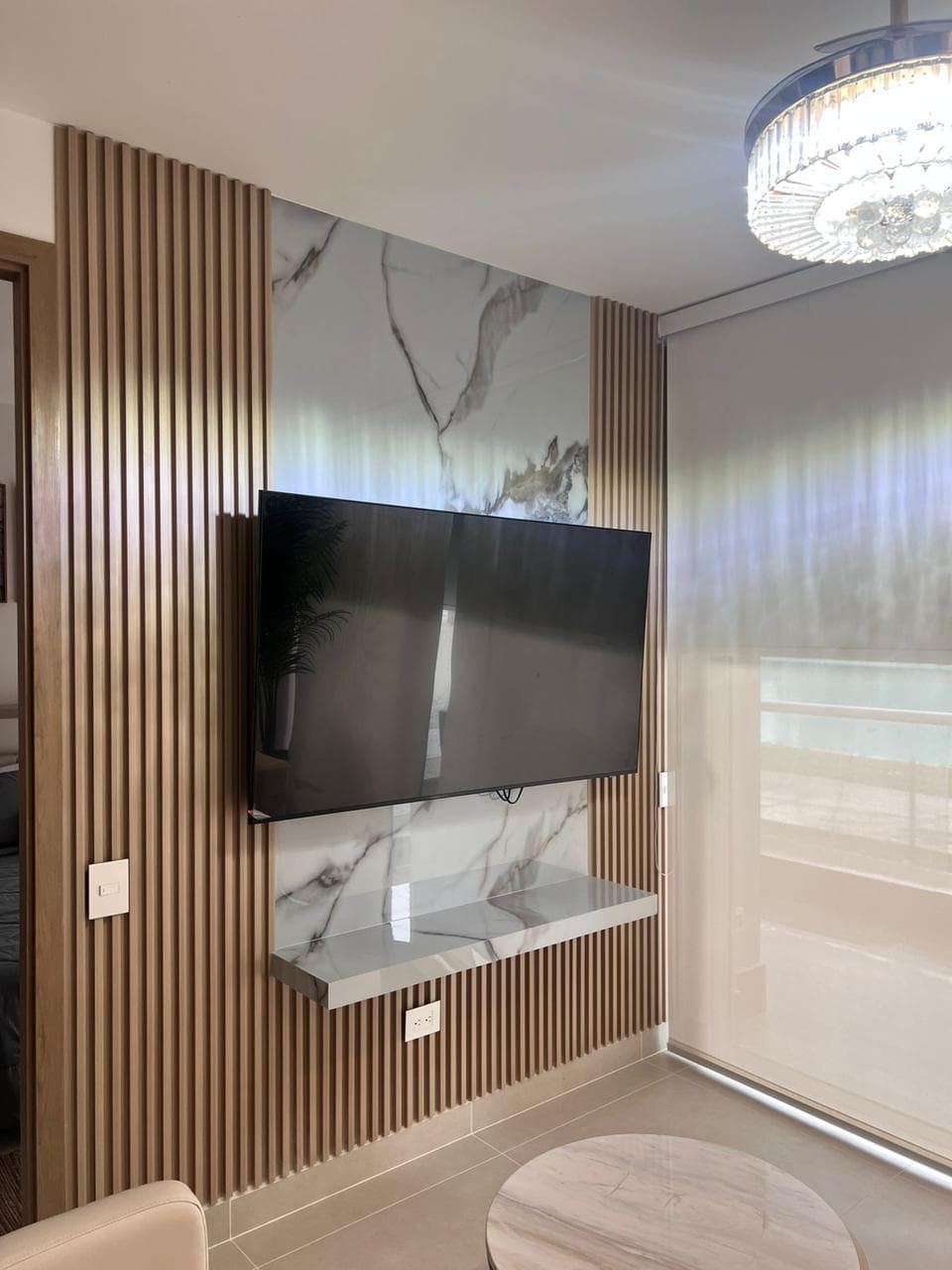 Panel de listones de madera con mármol calacatta y lámpara de techo, instalado por Reddy