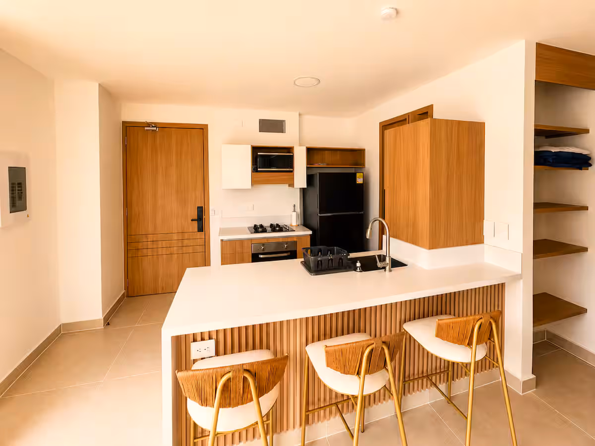 Cocina con barra revestida en listones, taburetes y puerta de madera