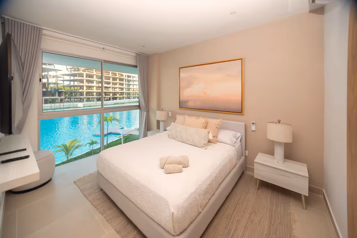 Habitación con cama, cuadro de cielo, lámparas y vista a la laguna