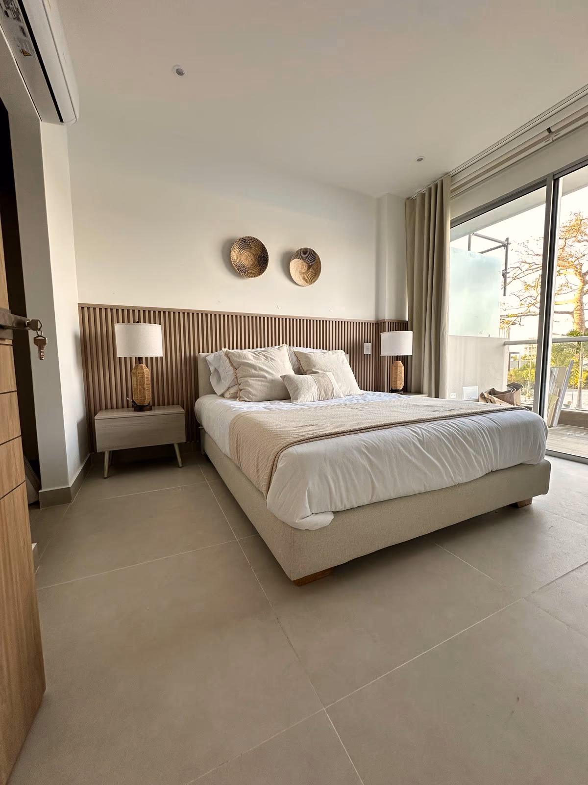 Habitación con cabecero de listones, lámparas colgantes, terraza y vista arbolada