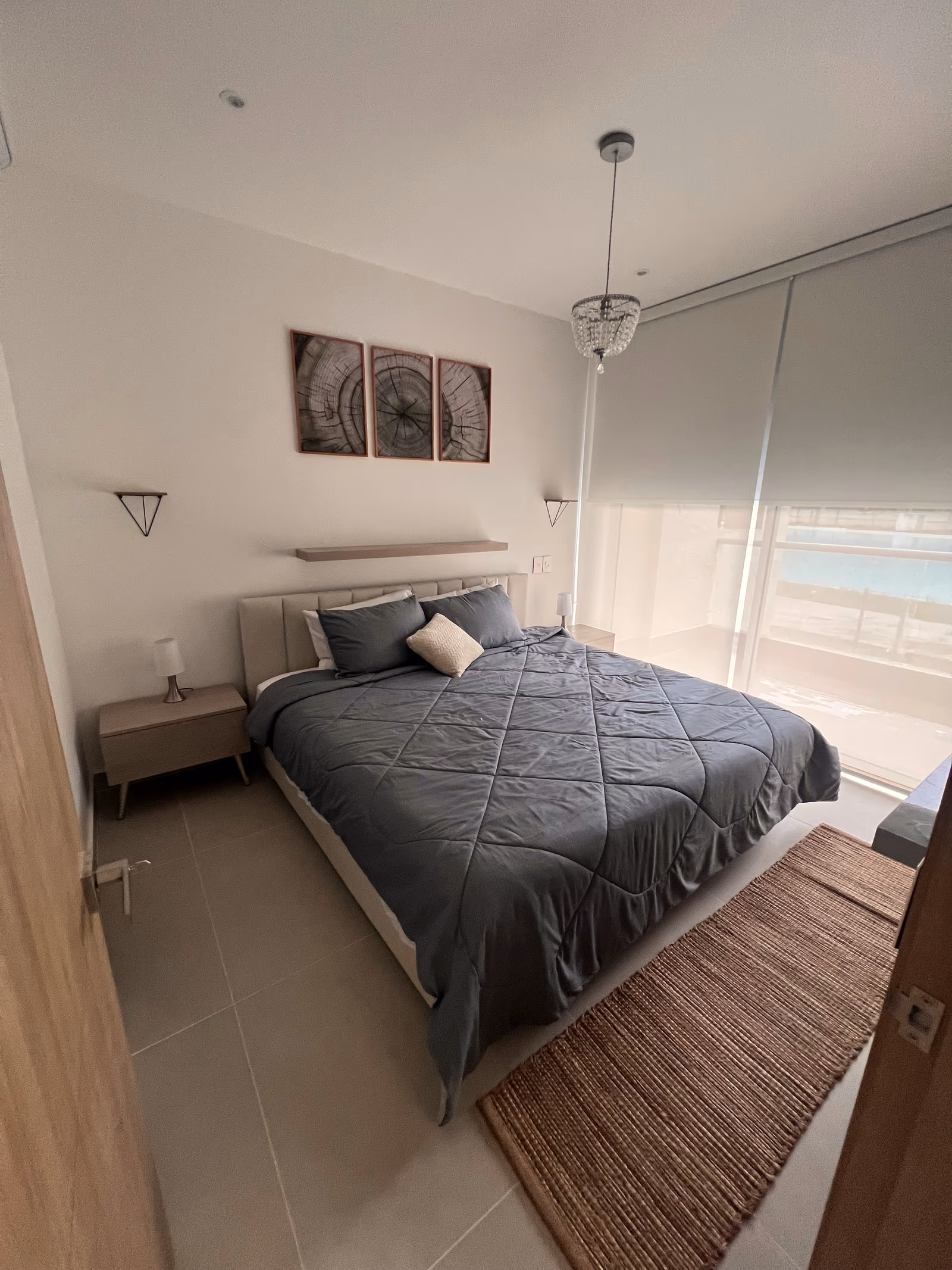 Habitación con edredón gris y cortina black-out abierta a la vista