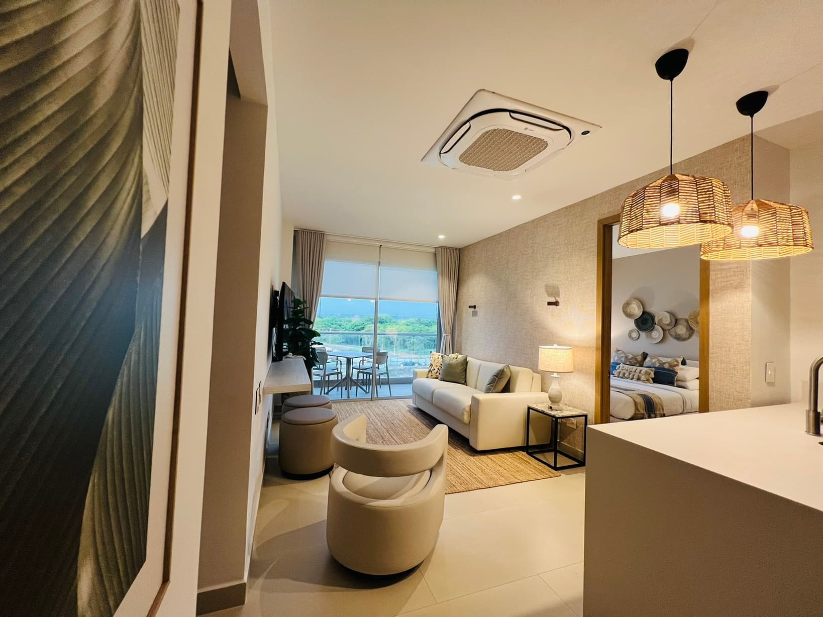 Sala-comedor amoblada por Reddy en Cartagena con cuadro de hoja, lámparas mimbre y vista a terraza