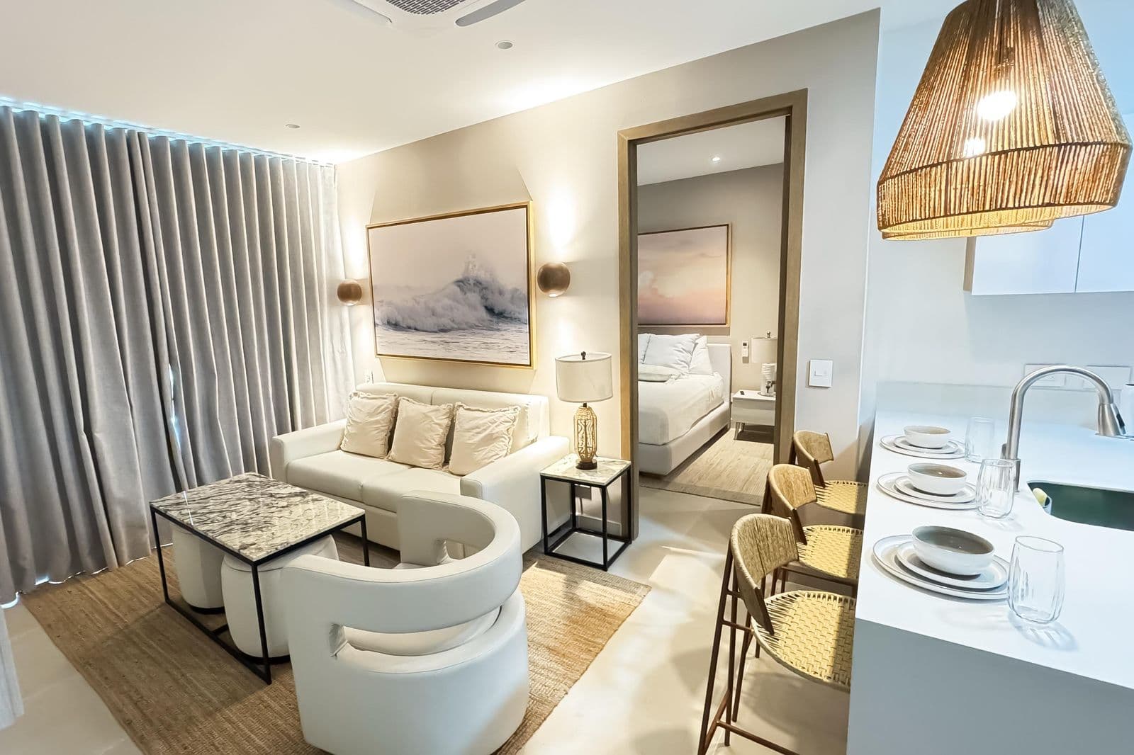 Sala con sofá blanco, sillas redondas tapizadas y mesa de centro mármol en apartamento dotado por Reddy en Cartagena