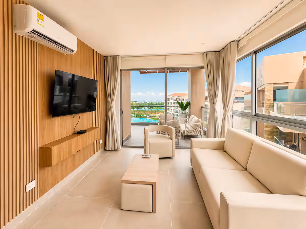 Sala con muro de listones de madera, TV, cortinas y terraza con vista a la laguna