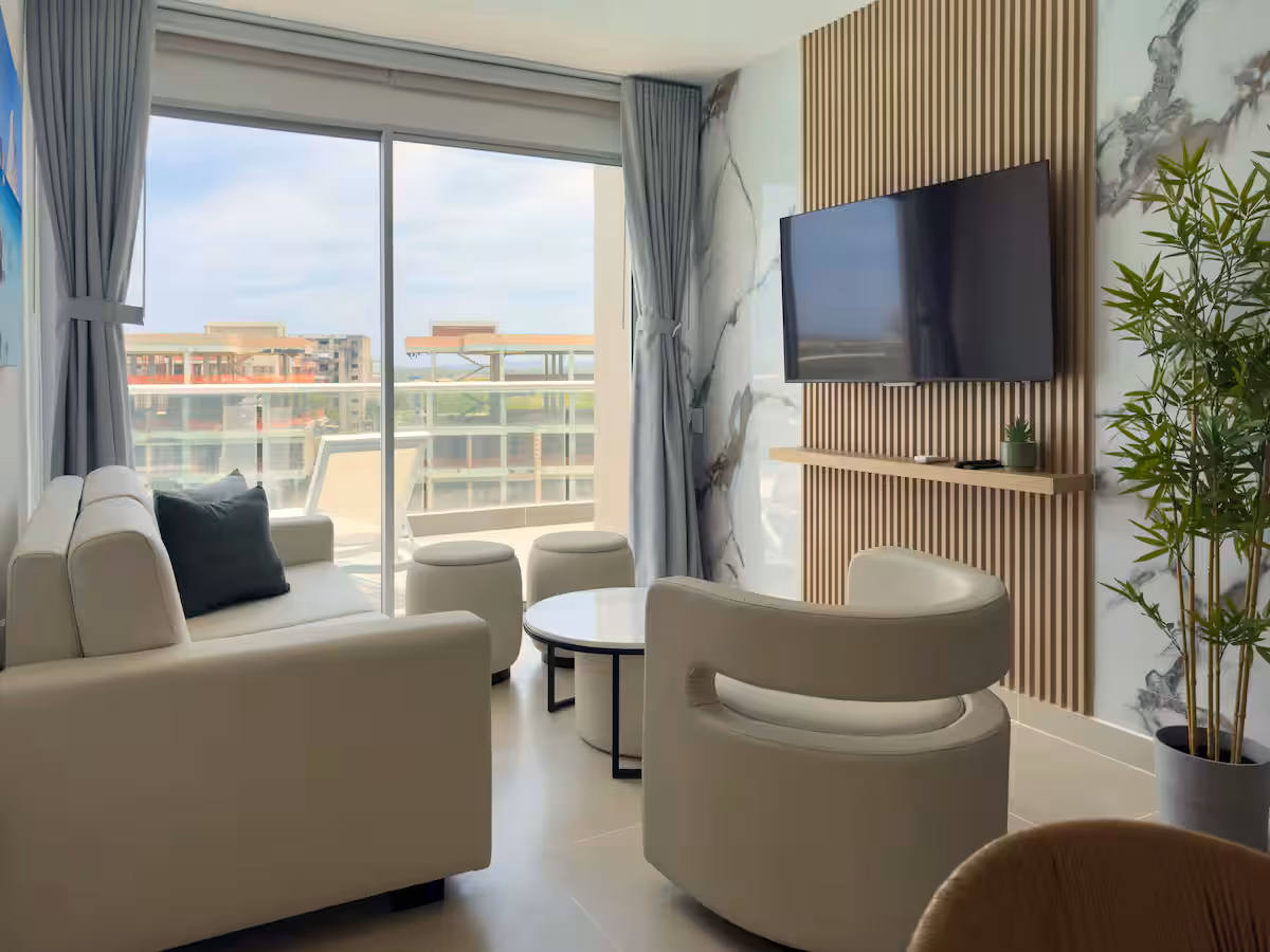 Sala con panel de listones y mármol, TV, ventanal y sofás blancos