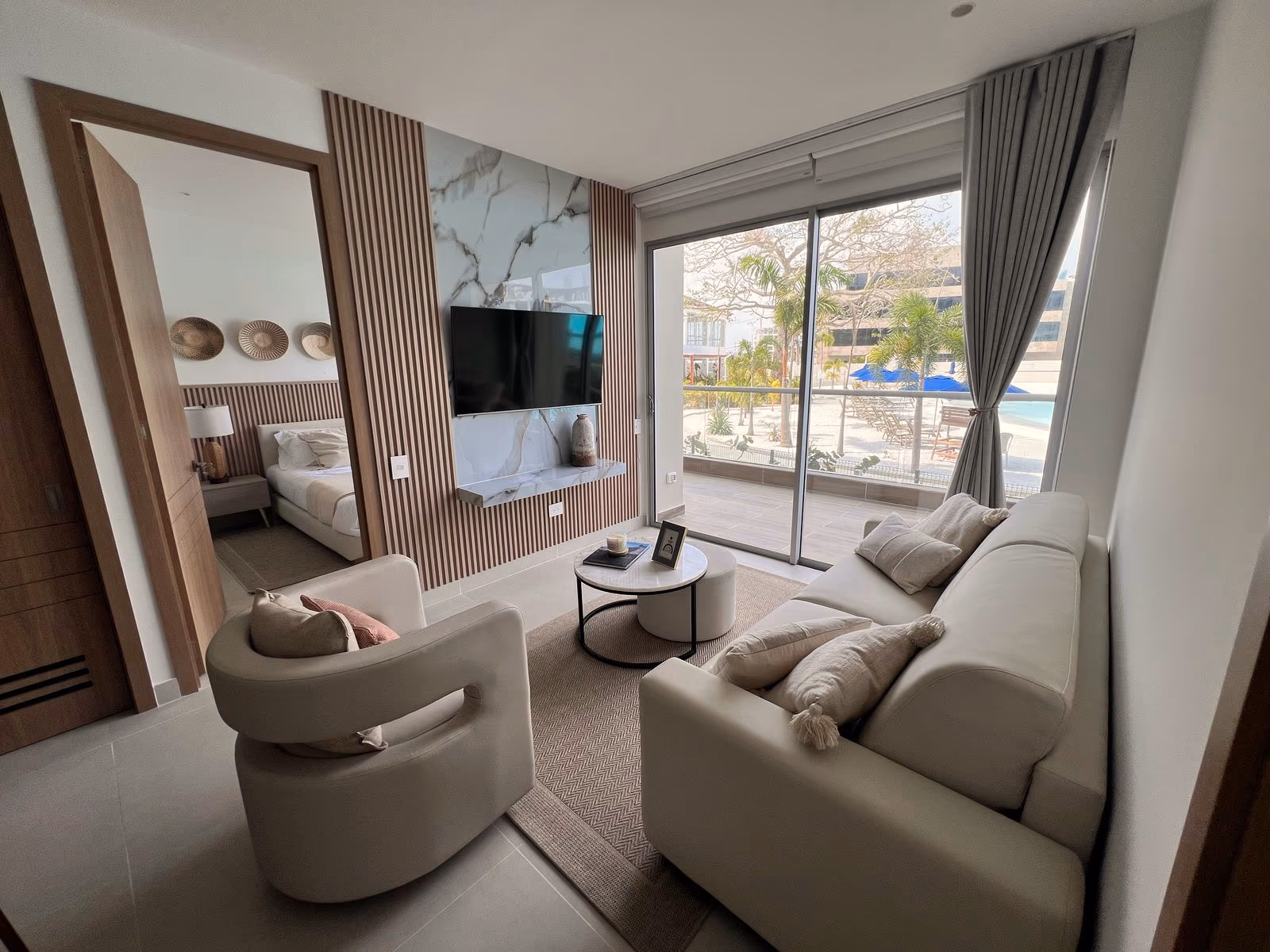 Sala con panel de listones y mármol, TV y ventanal hacia la piscina en apartamento dotado por Reddy