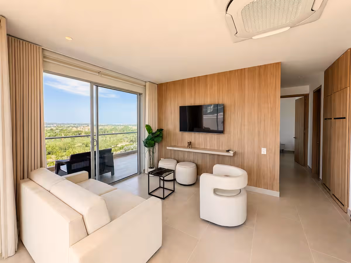 Sala con pared de madera, TV, sofá, butacas y terraza con vista