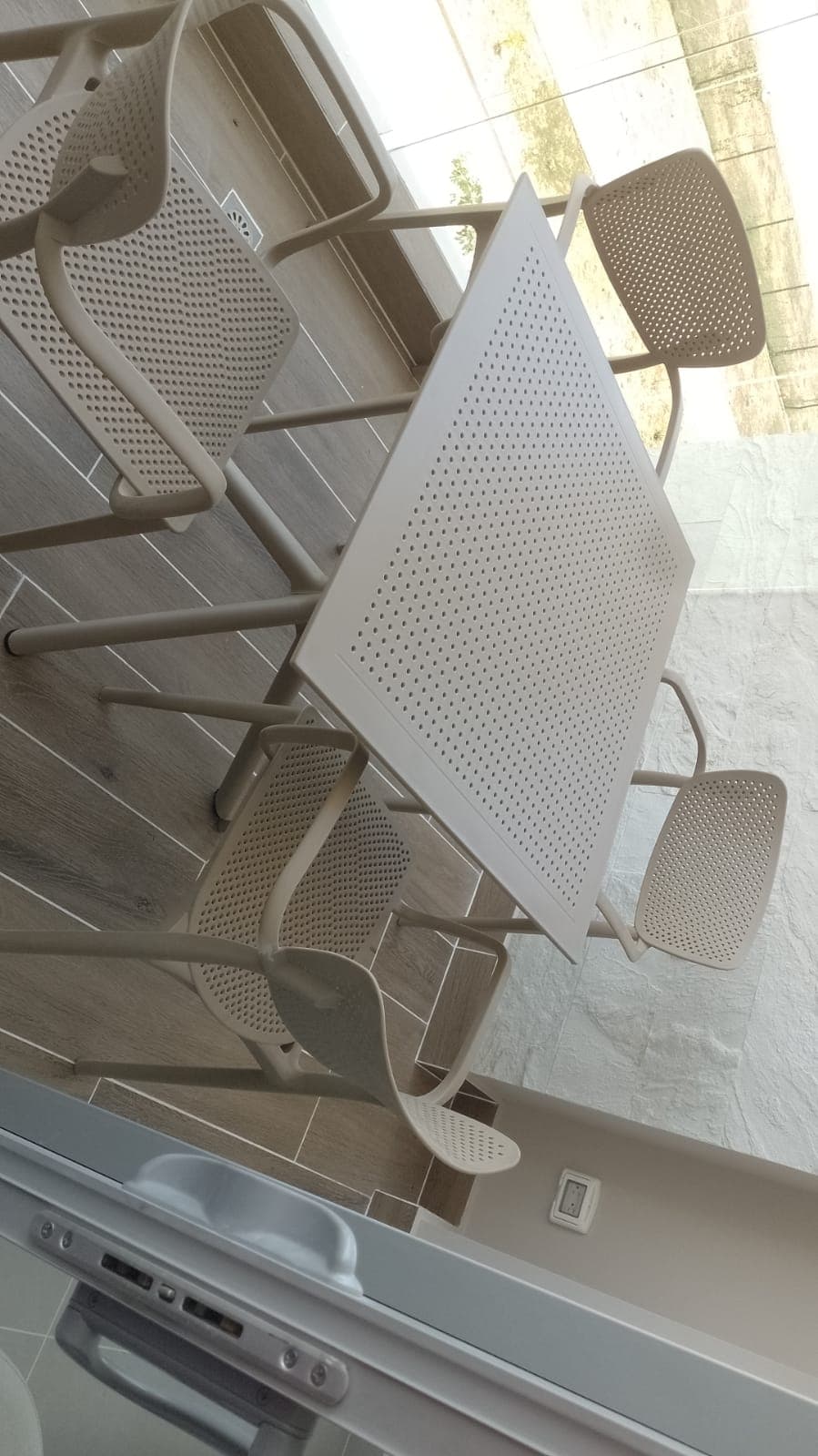 Vista cenital de mesa cuadrada con sillas perforadas en terraza