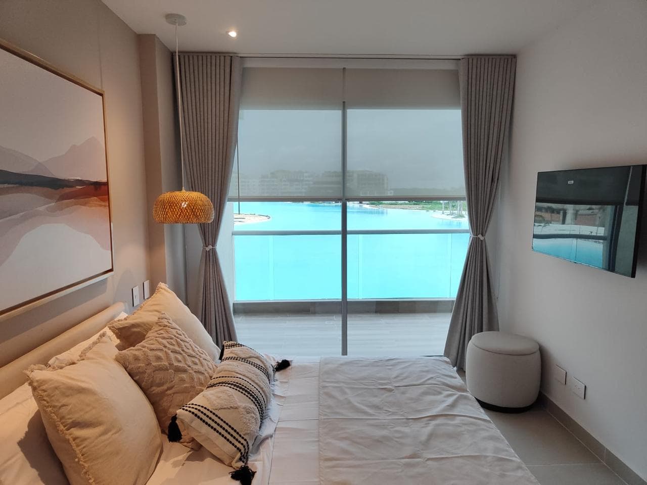 Habitación amoblada con cama vestida, cortinas y la misma vista a la laguna