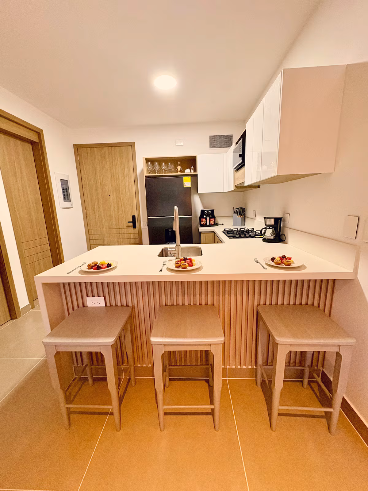 Cocina con barra en madera, tres butacas y fruta servida