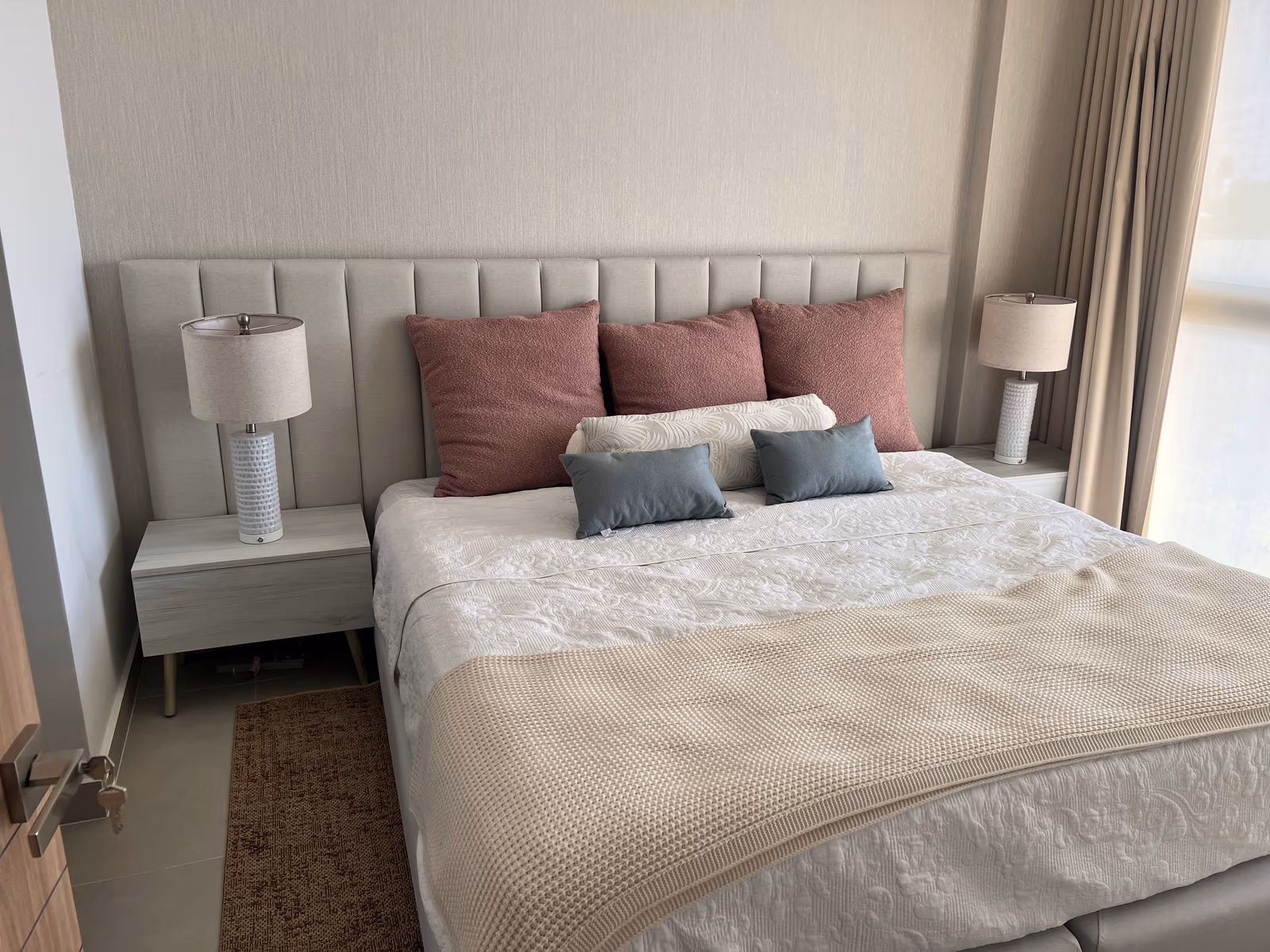 Habitación king con cabecera tapizada, lámparas de mesa y lencería blanca